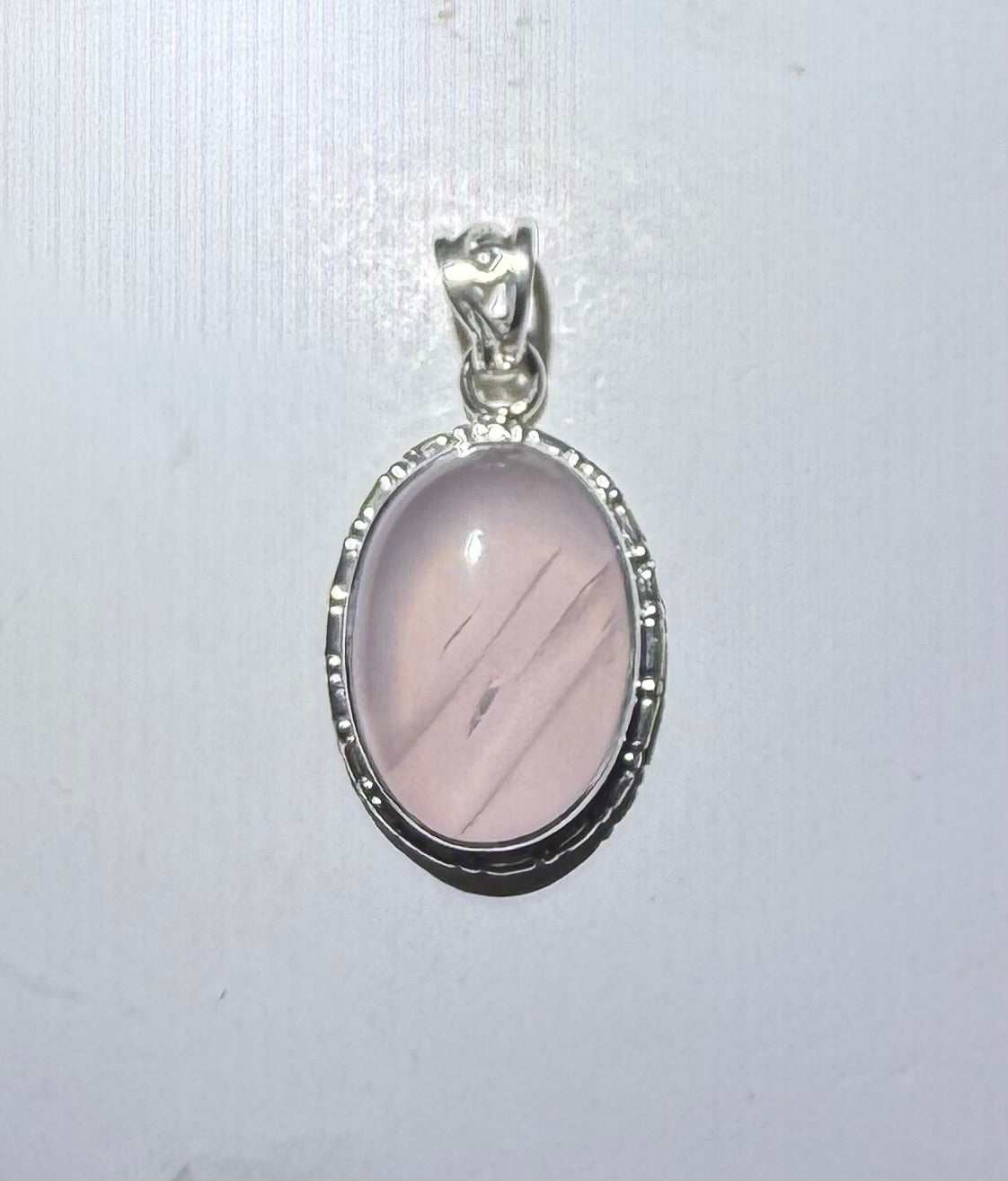 Colgante ovalado de cuarzo rosa con borde festoneado en plata de ley