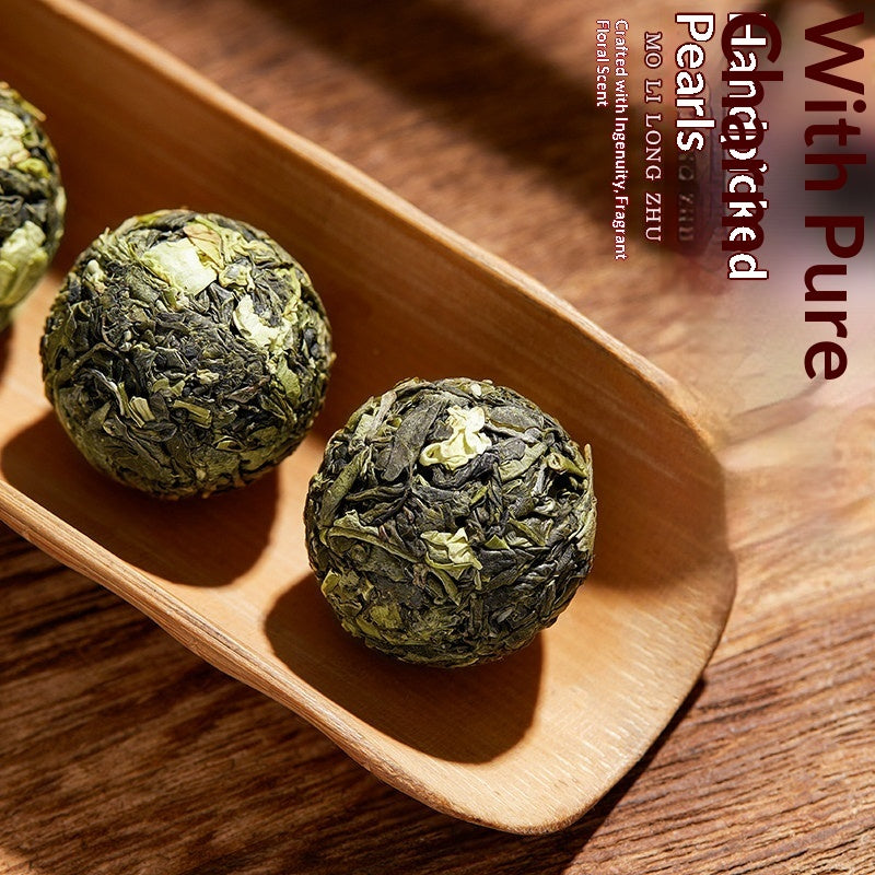 Three round green tea pearls resting in a wooden scoop on a wooden table, with vertical text on the right side reading 'With Pure Long Zhu Pearls' and 'Created with responsibly PGOYEN tea blend.'.