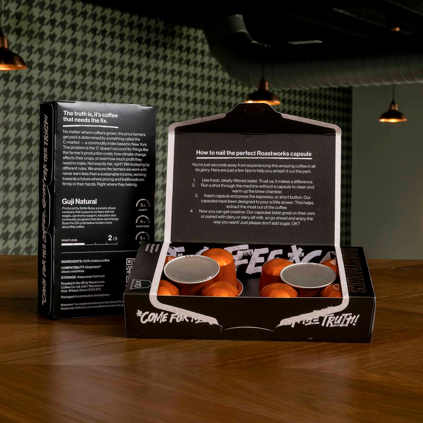 Roastworks coffee capsule packaging on a wooden surface with a dark background